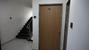 A wooden door with a number plate, a staircase with metal railings, and a tiled floor. - Ravechi Krupa Hotel (Dwarka)