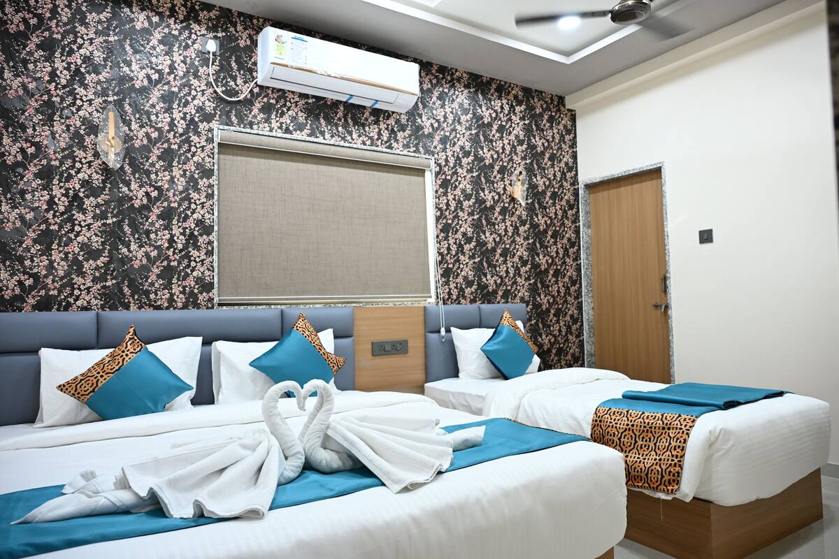Ein Hotelzimmer mit zwei Betten, einem großen Fenster, einer Klimaanlage und einem Deckenventilator.