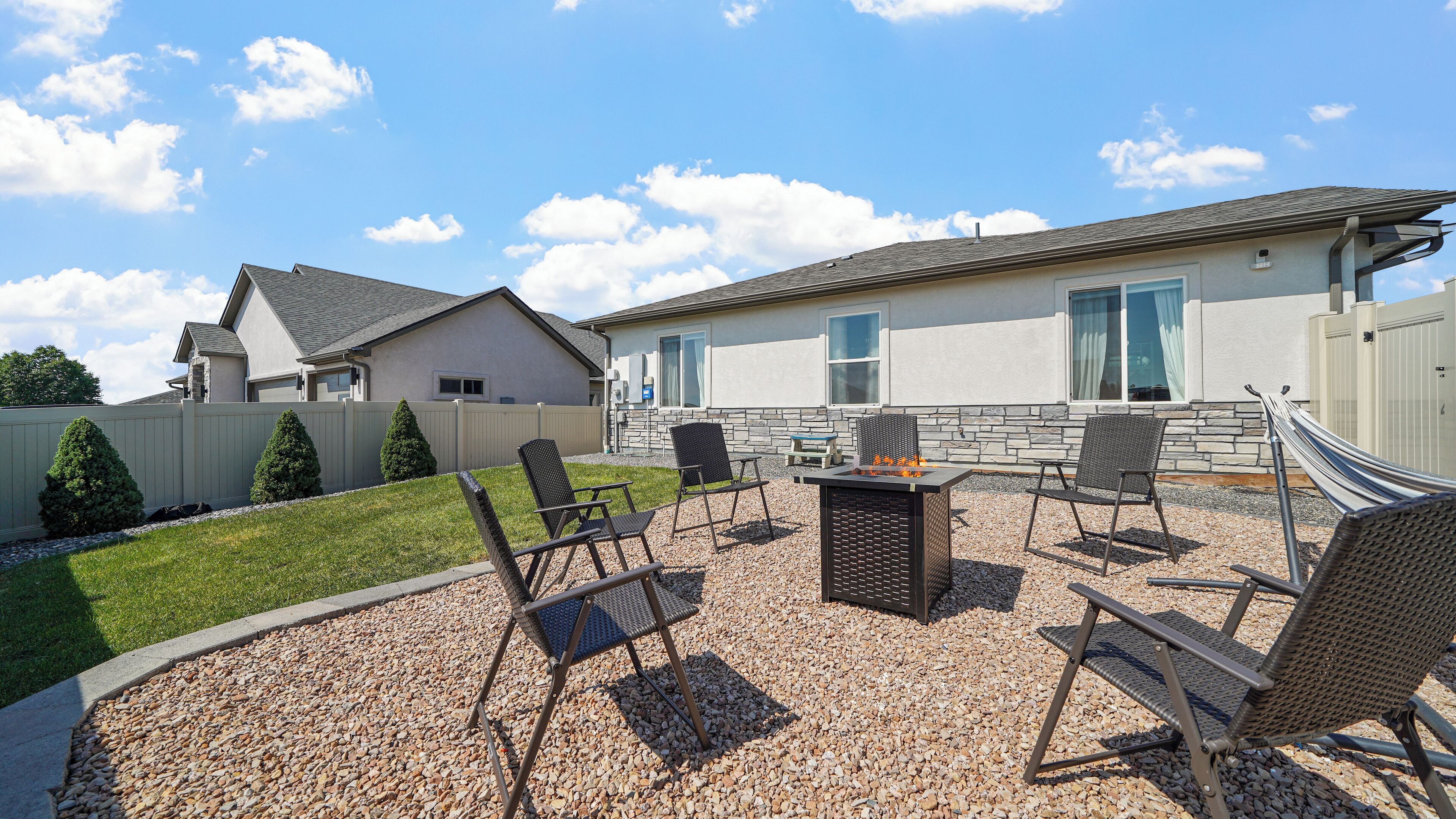An outdoor patio with a fire pit, seating, and a stone wall.