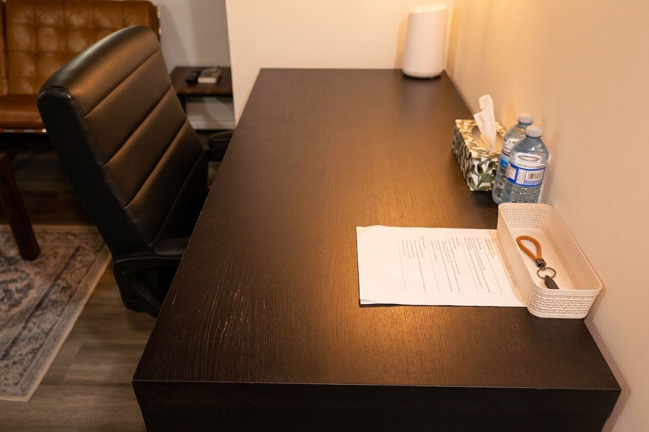 A wooden table with a document and a white basket with a keychain.