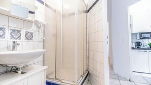 A modern bathroom with a white sink, a glass shower enclosure, and patterned tiles. - Modern 2BR Apt Longstay Sleeps 5 (Vienna)