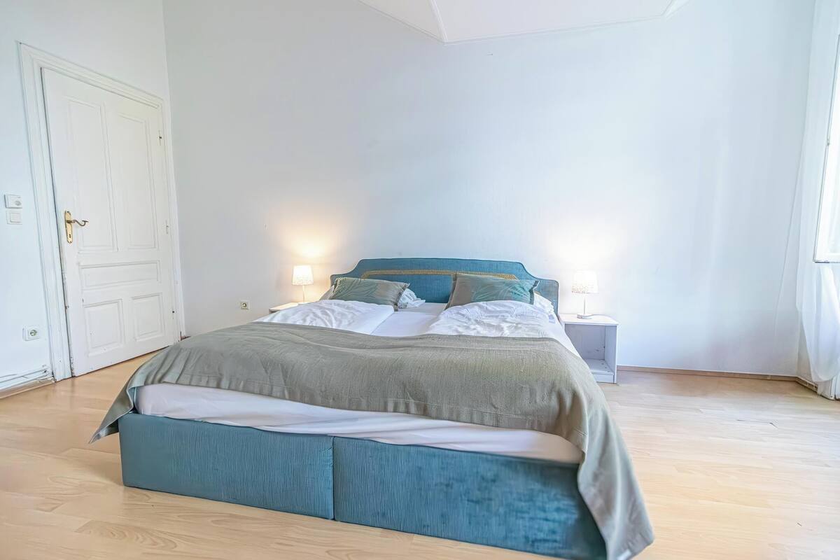 A bedroom with a bed, bedside tables, and a door.