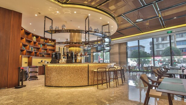 Un área de bar moderna con una barra curva, asientos y vistas al exterior.