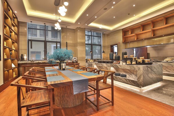 A modern hotel lobby with a long wooden reception desk, comfortable seating, and a large window providing natural light.