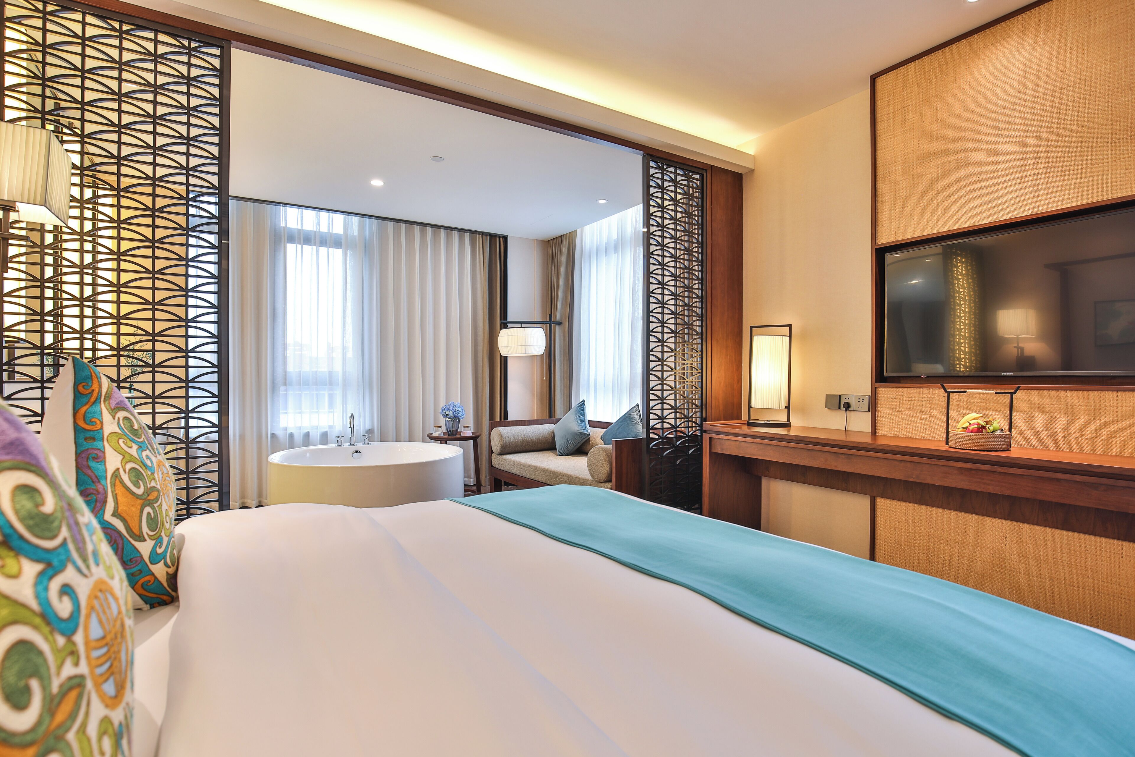Une chambre d’hôtel avec un lit, un bureau, une télévision, un lavabo et une fenêtre avec des rideaux.