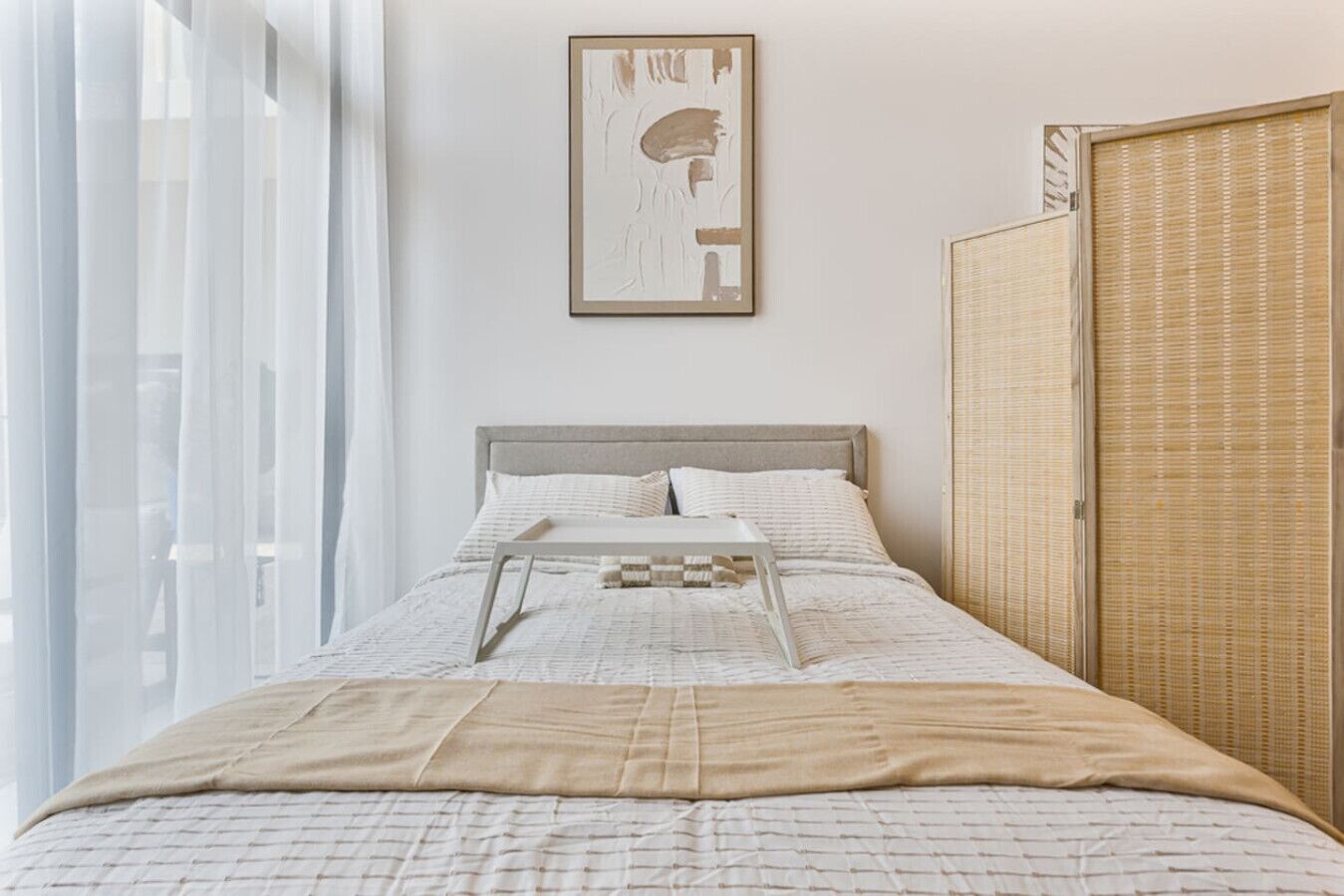 A neatly arranged bedroom with a bed, a bedside table, and a framed artwork on the wall.