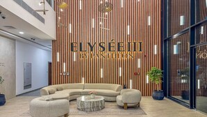 Een moderne lobby met een gebogen bank, een ronde salontafel en potplanten.
