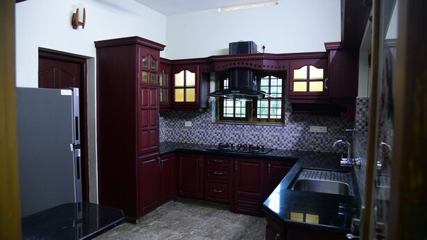 Una cucina con pensili in legno scuro, un frigorifero in acciaio inossidabile e un piano di lavoro nero.