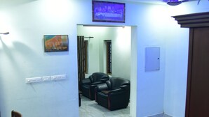 Una stanza con pavimento in marmo, un tavolo da pranzo con sedie, un divano, una ventola a soffitto e un televisore fissato al muro.