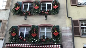 Um edifício com várias janelas enfeitadas com decorações de Natal, incluindo grinaldas e enfeites em formato de coração.