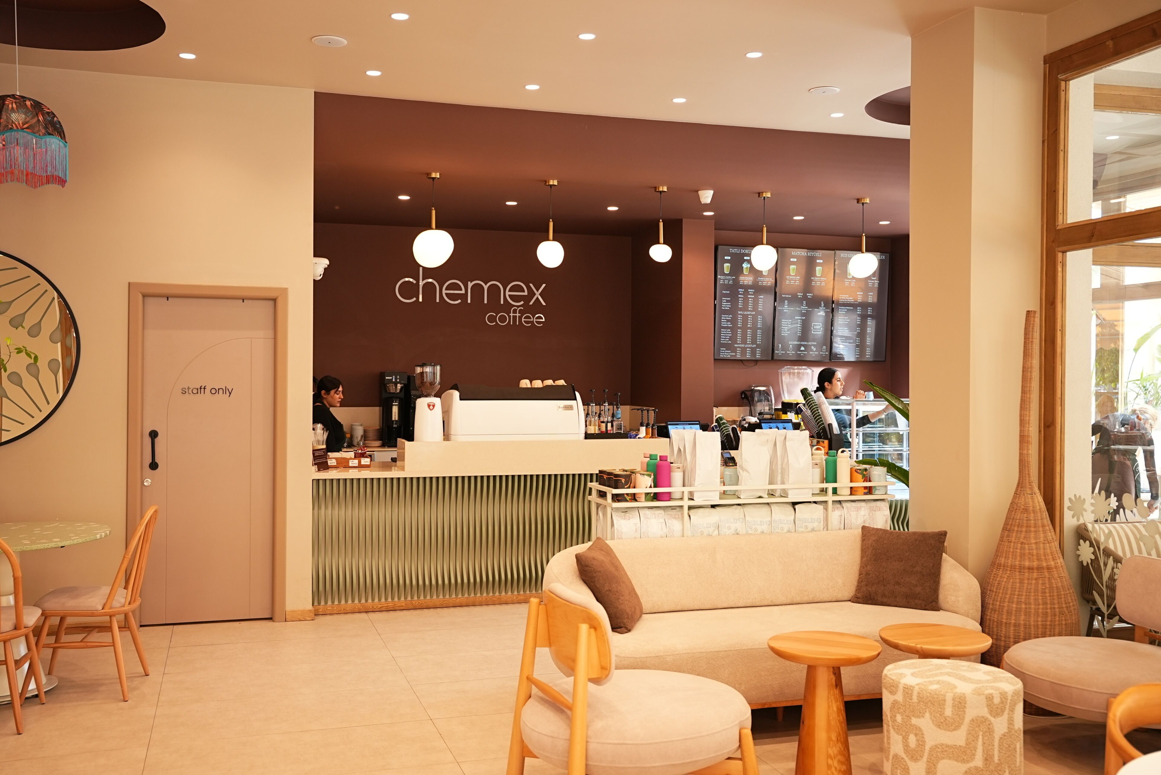 Un interior de cafetería moderno con mostrador, zona de estar y un panel de menú.