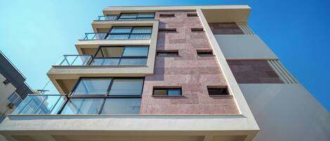Un edificio de varios pisos con un diseño arquitectónico moderno, que cuenta con grandes ventanales y balcones.