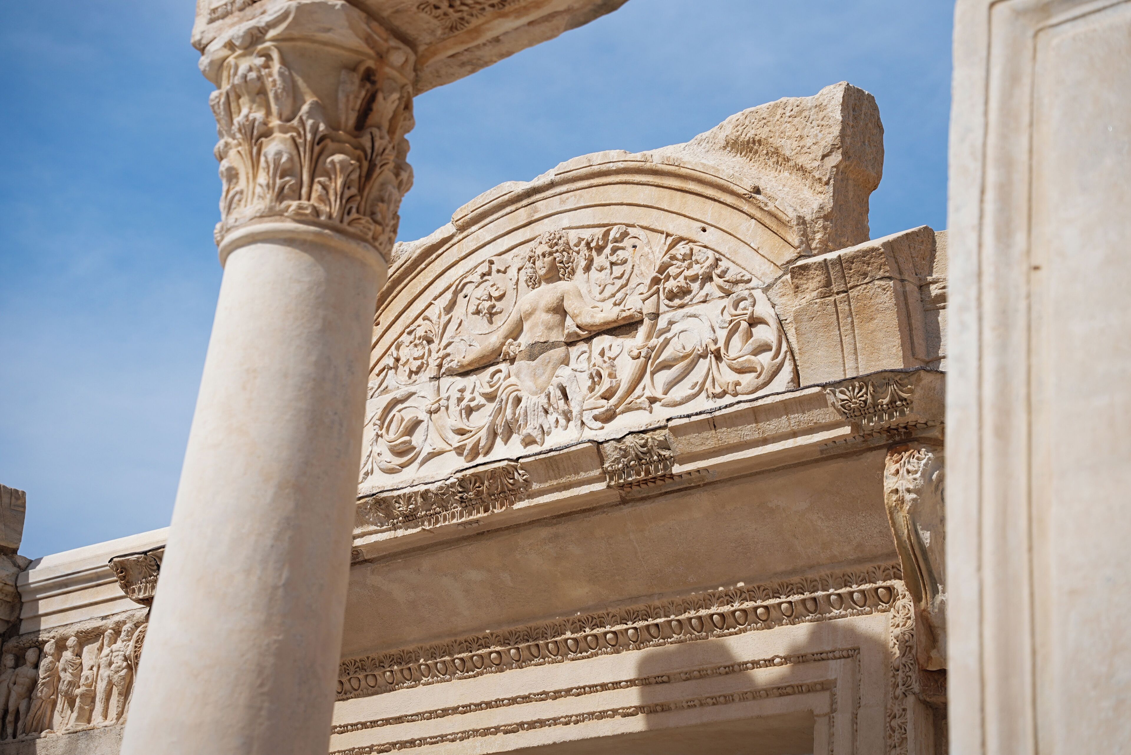 A detailed stone carving on a building's facade, featuring a central figure and decorative elements.