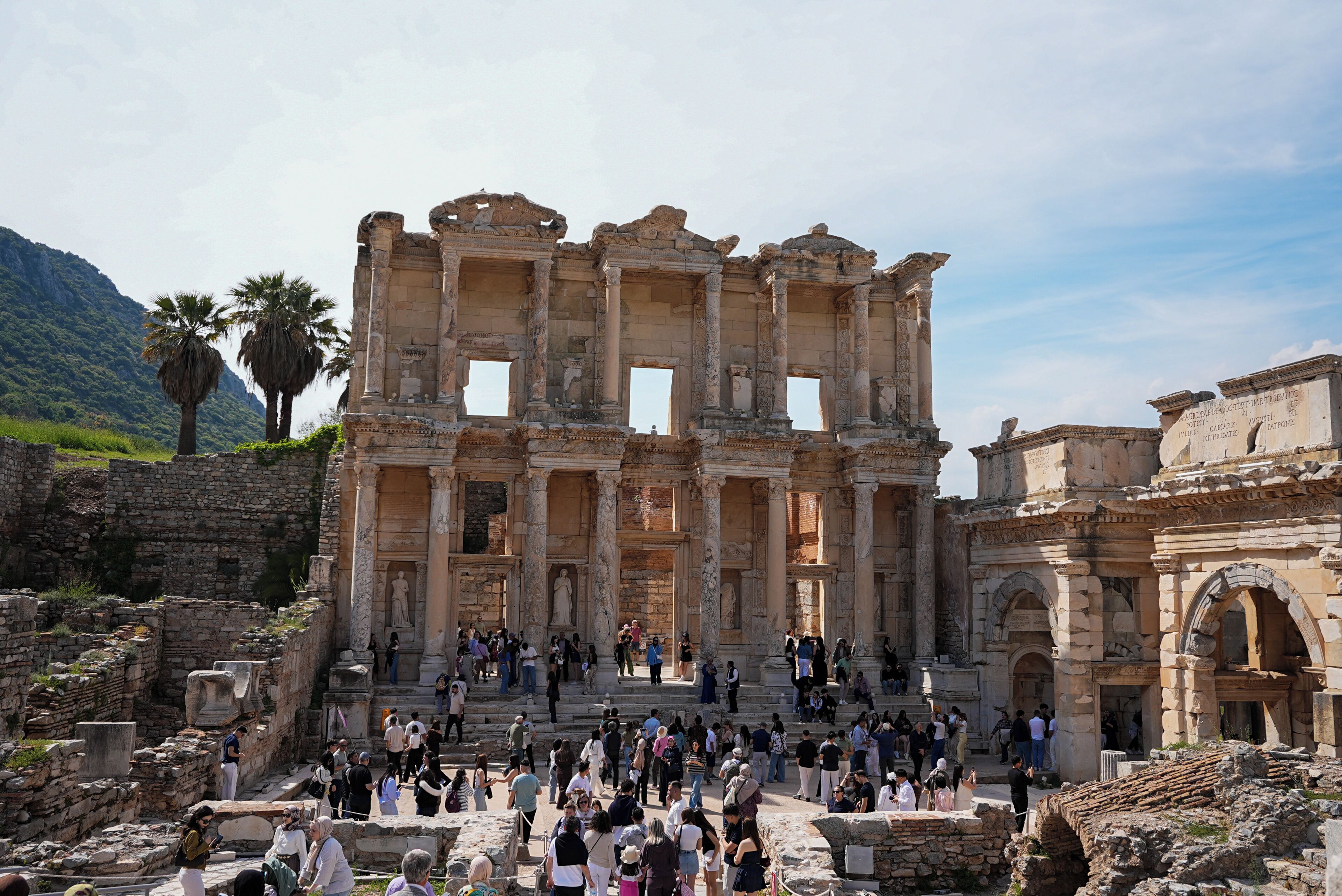 An ancient ruin with columns and steps, surrounded by tourists.