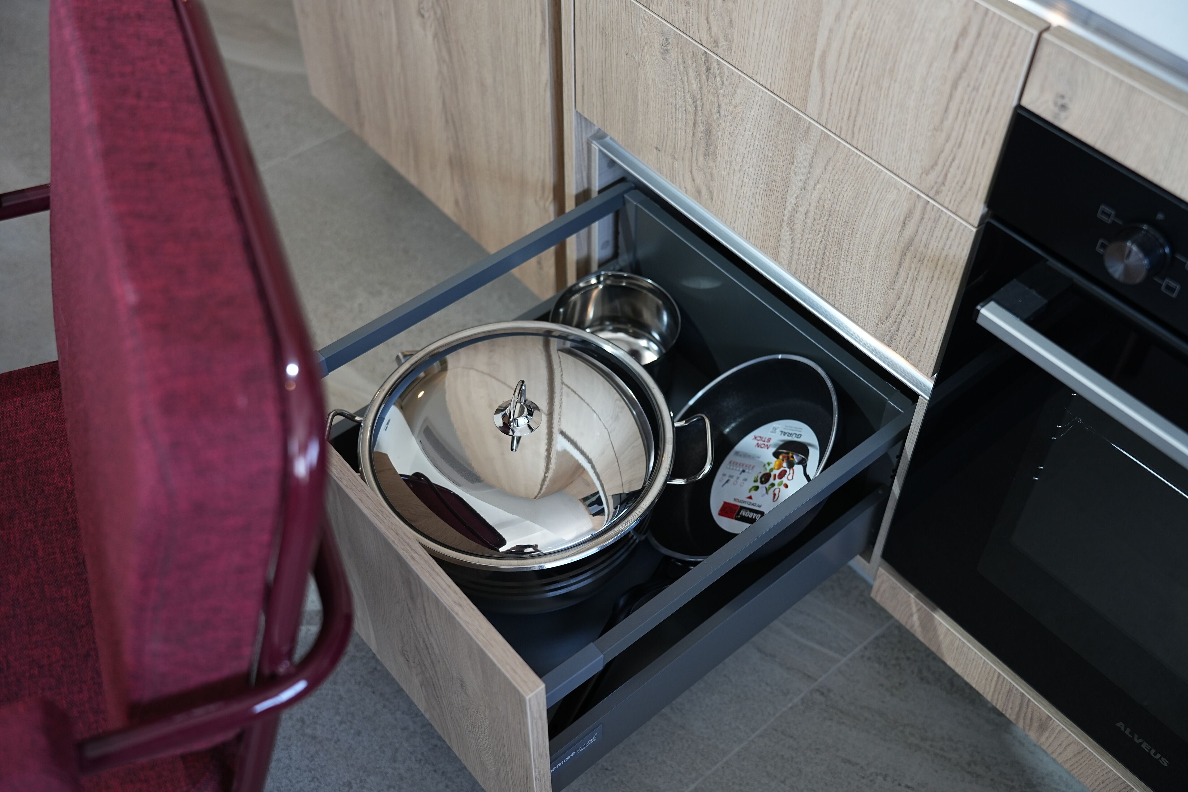 A kitchen with a drawer containing pots and pans.