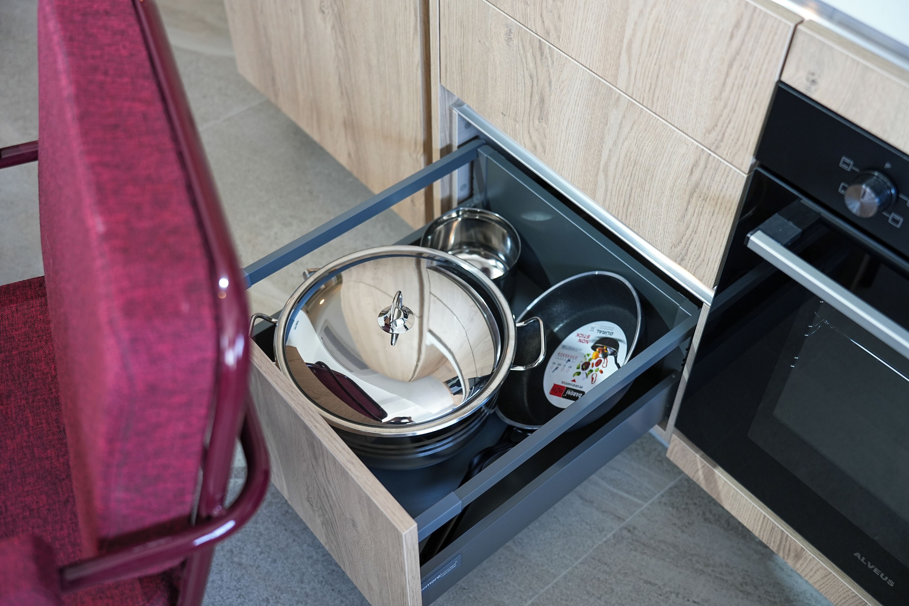 A kitchen with a drawer containing pots and pans.