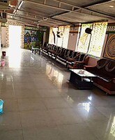 A spacious hall with rows of seating, a central table, and a mural on the wall.