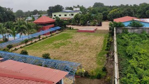 A rural area with a large open field, a few buildings, and a small water body. - Vrundavan Village Resort and Home Stay (Garudeshwar)
