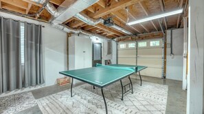Amplio espacio interior con mesa de ping pong, pared blanca y puerta de garaje.