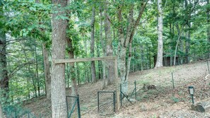 Un área boscosa con una estructura de madera, posiblemente un refugio, rodeada de árboles y una zona cercada.