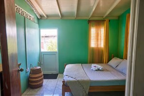 A room with a bed, a window, a door, and a wall-mounted sign. - Peaceful Haven | 2BR | Kitchen | Parking (Roseau)