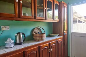 Een keuken met houten kastjes, een waterkoker, een mand en een spoelbak.
