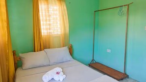 Un lit simple avec une tête de lit en bois, une balançoire et une fenêtre avec des rideaux.