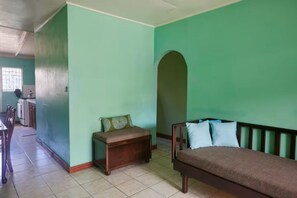 A room with a bed, a bench, and a dining area with chairs and a table. - Roseau Escape | 2BR | Free Parking | Sleeps 4 (Roseau)