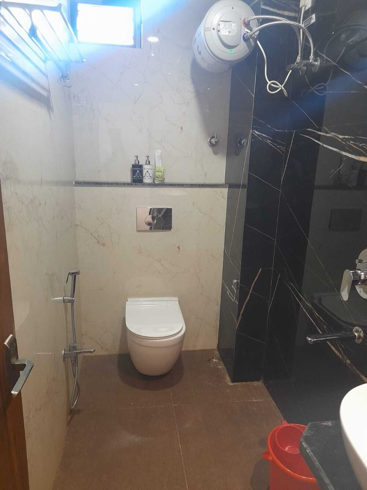 Un baño con inodoro, ducha y lavamanos. Hay artículos de aseo en la pared.