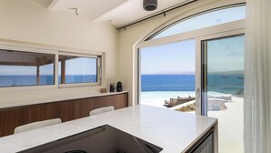 Una cuina moderna amb una illa gran, zona de menjador i vista al mar.