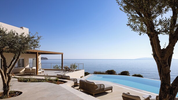 Zona de piscina exterior moderna amb gandules i una pèrgola amb vista al mar.