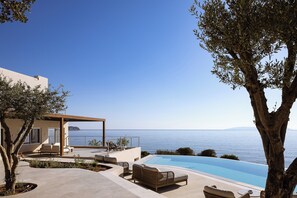 Area piscina esterna moderna con sedie a sdraio e un gazebo con vista sul mare.