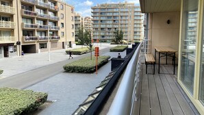 Un edificio residencial con varios balcones, un sendero peatonal y una pequeña zona ajardinada.