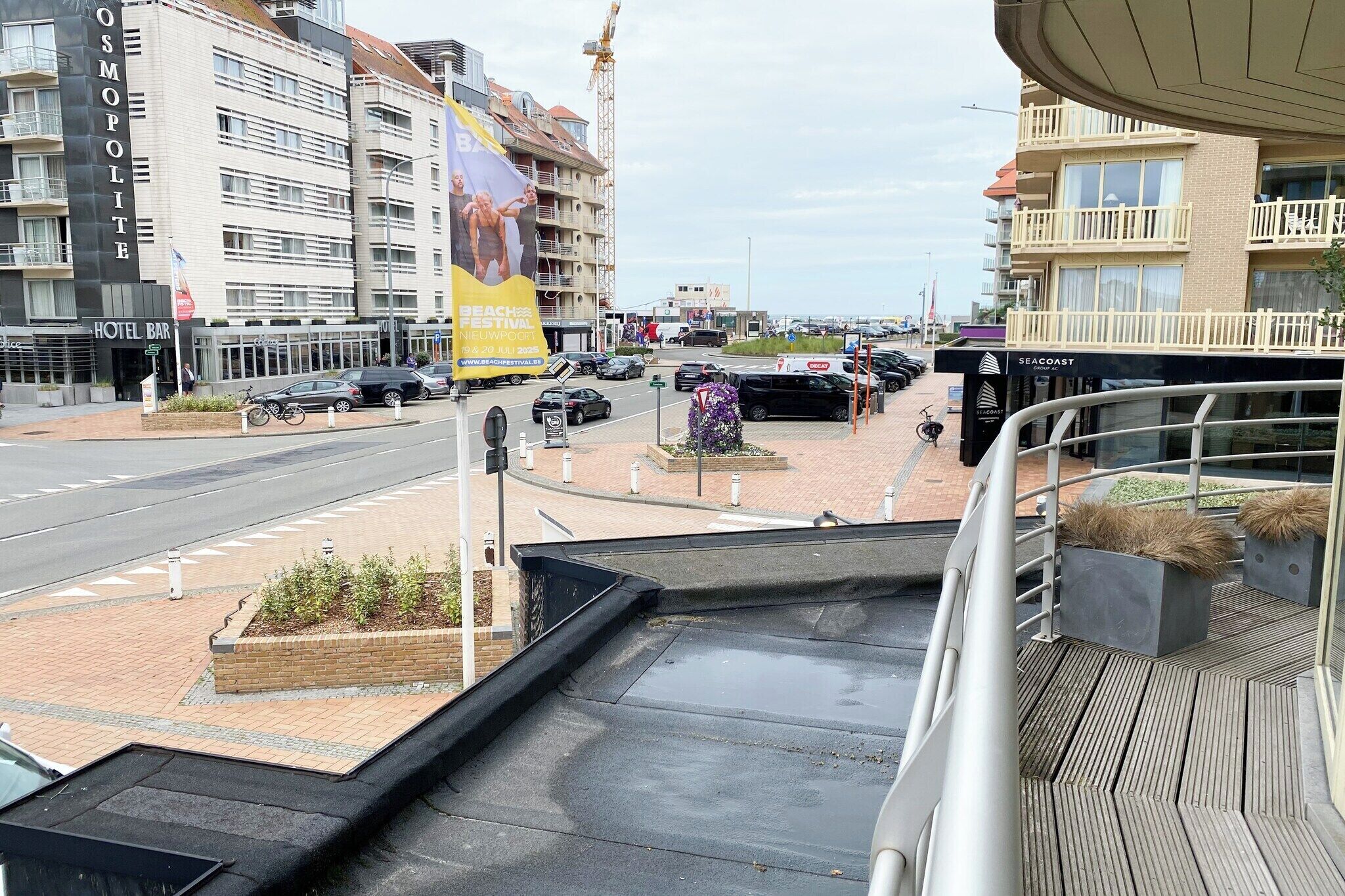 Ein Hotel mit Balkon, Blick auf die Straße und einem Banner für ein Strandfestival.