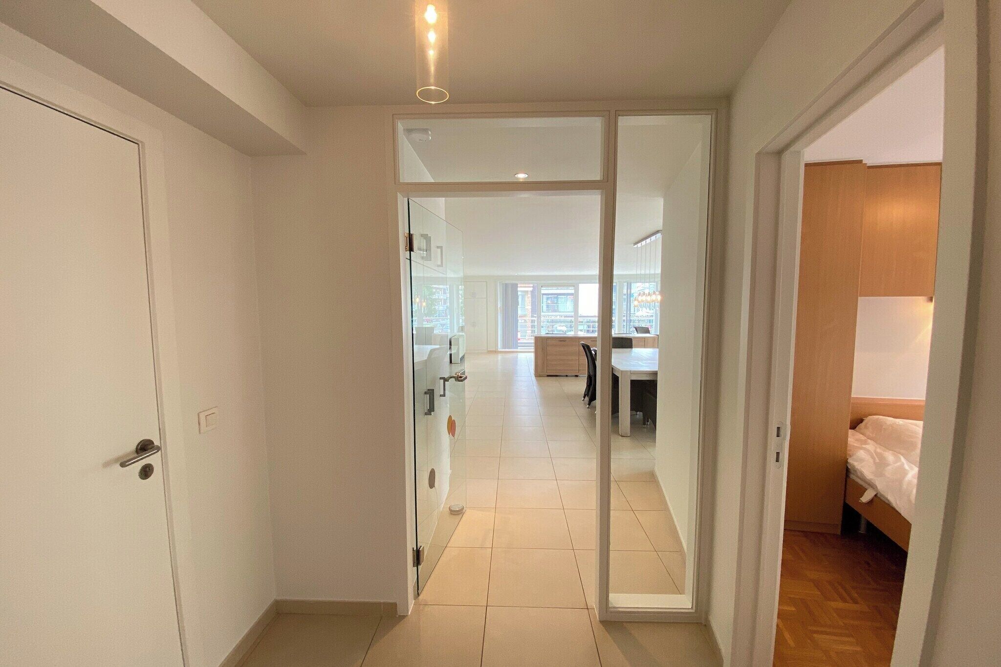 A corridor with a sliding glass door leading to a bedroom with a wooden floor.