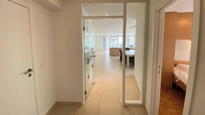 Un pasillo con una puerta corrediza de vidrio que da a un dormitorio con piso de madera.