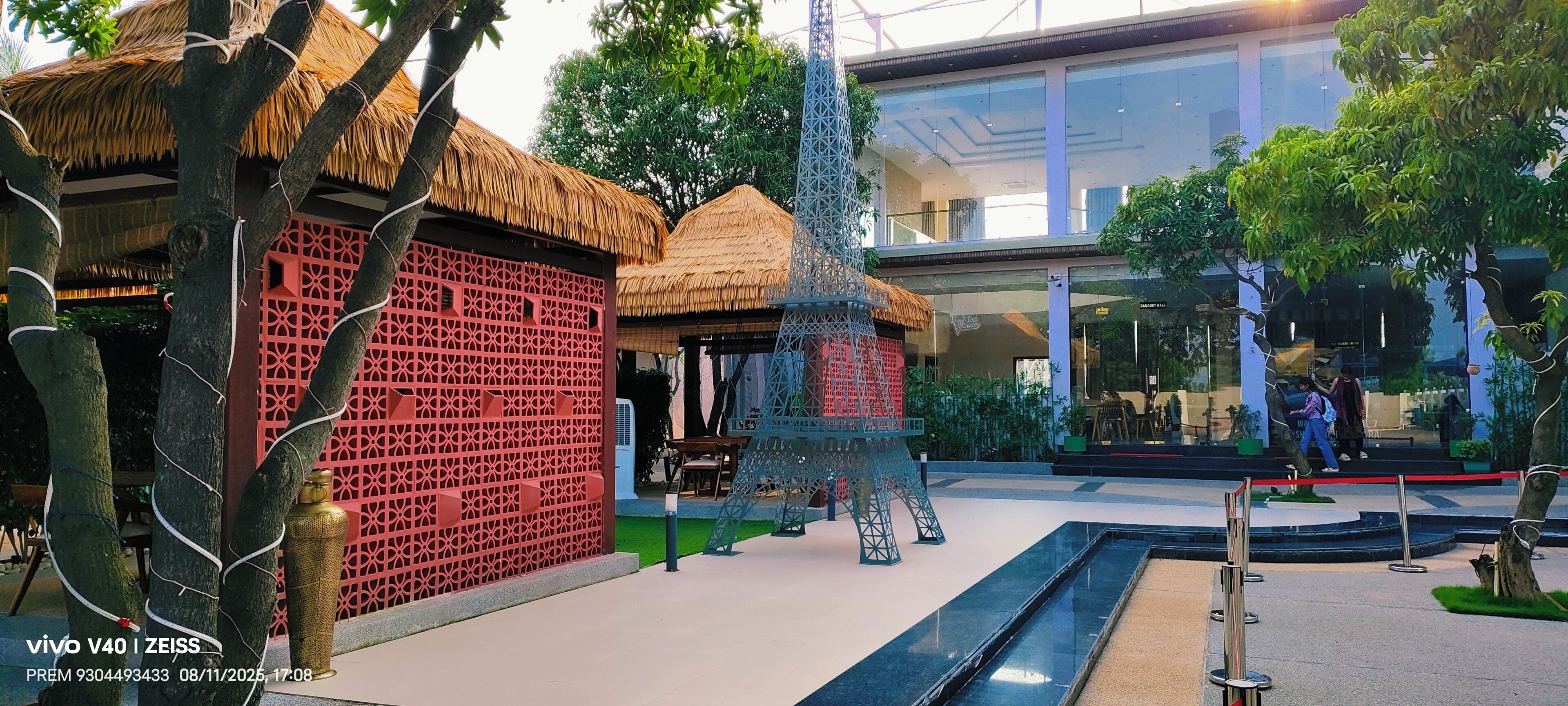A modern building with a glass facade, a thatched-roof structure, and a decorative Eiffel Tower model.