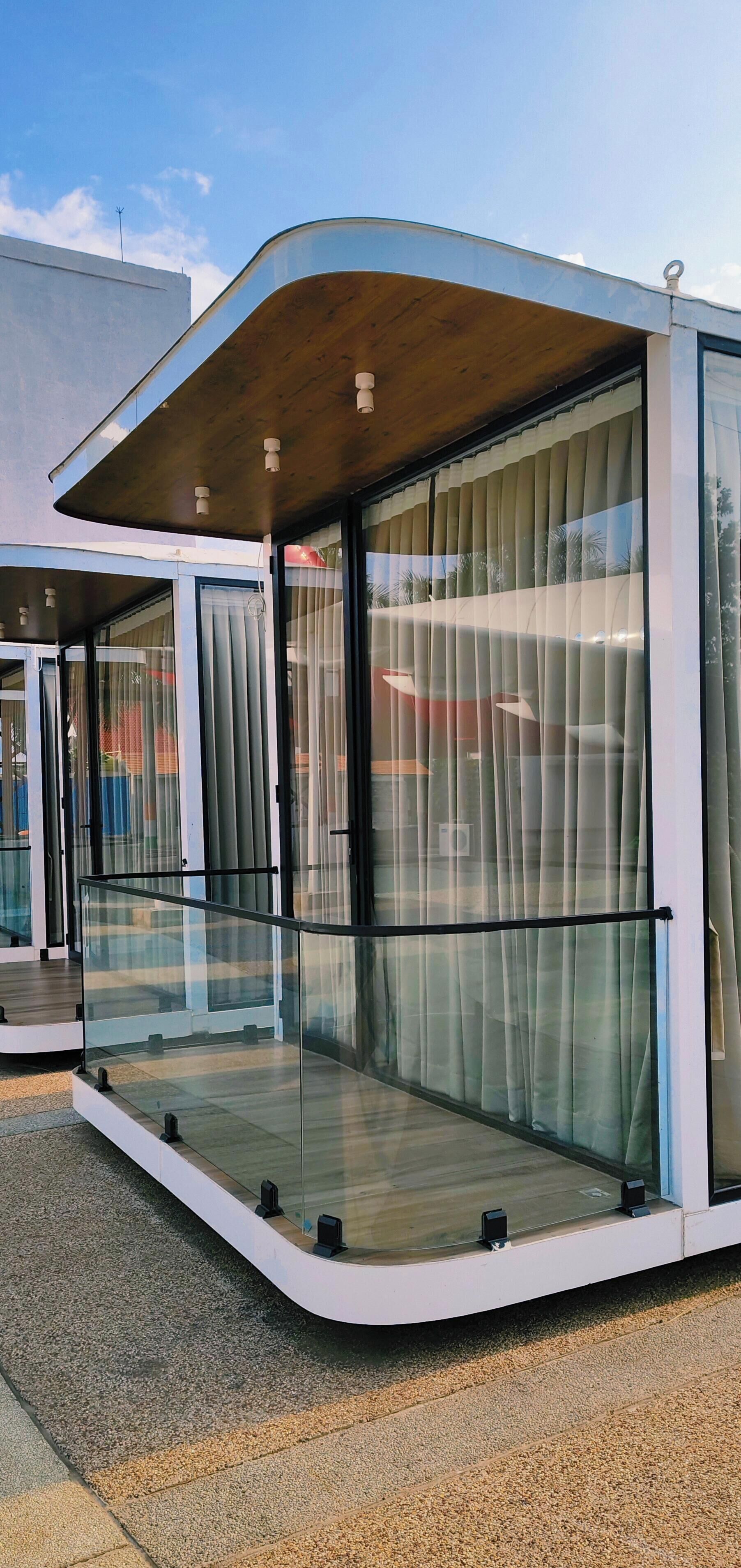 A modern, glass-walled room with a wooden ceiling and a curved design.