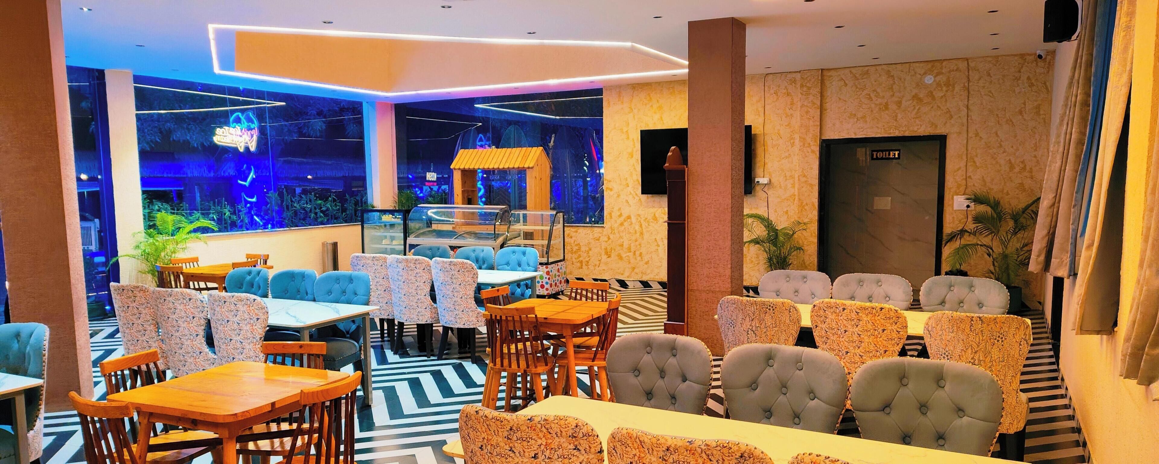 Ein Restaurant mit modernem Interieur, das eine Kombination aus Holz- und Polstermöbeln, eine Neonreklame und ein großes Fenster mit Außenblick bietet.