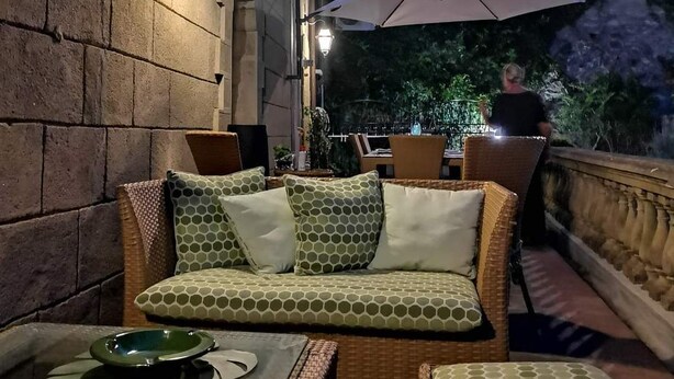 Ein Außenbereich mit Korbmöbeln, einem Tisch mit Tellern und einem großen Sonnenschirm.