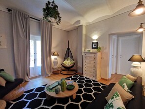 A living room with a sofa, a round coffee table, a hanging chair, a cabinet, and a door.