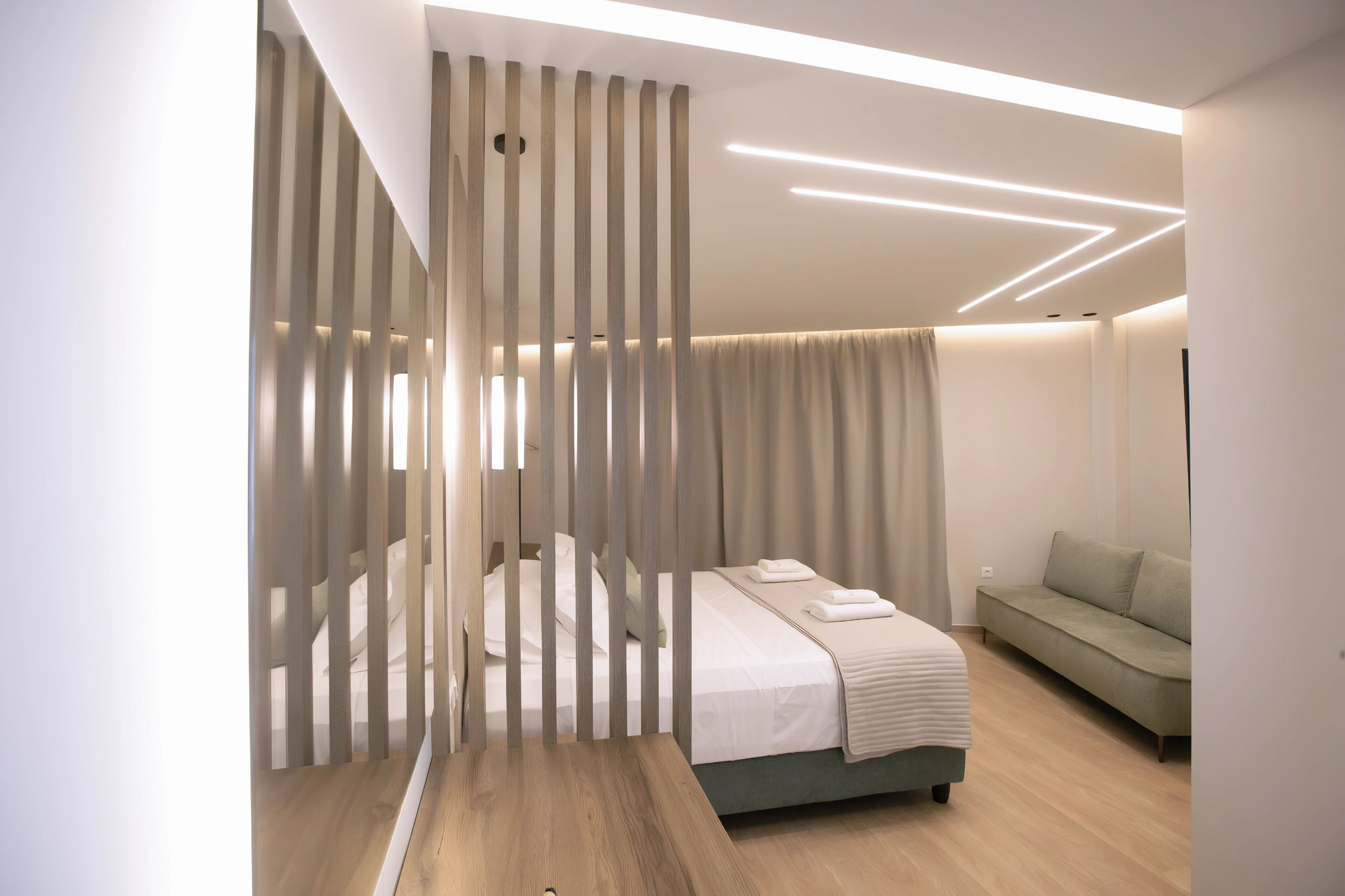 A modern bedroom with a bed, a sofa, and a partition with vertical slats.