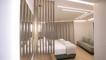 A modern bedroom with a bed, a sofa, and a partition with vertical slats.