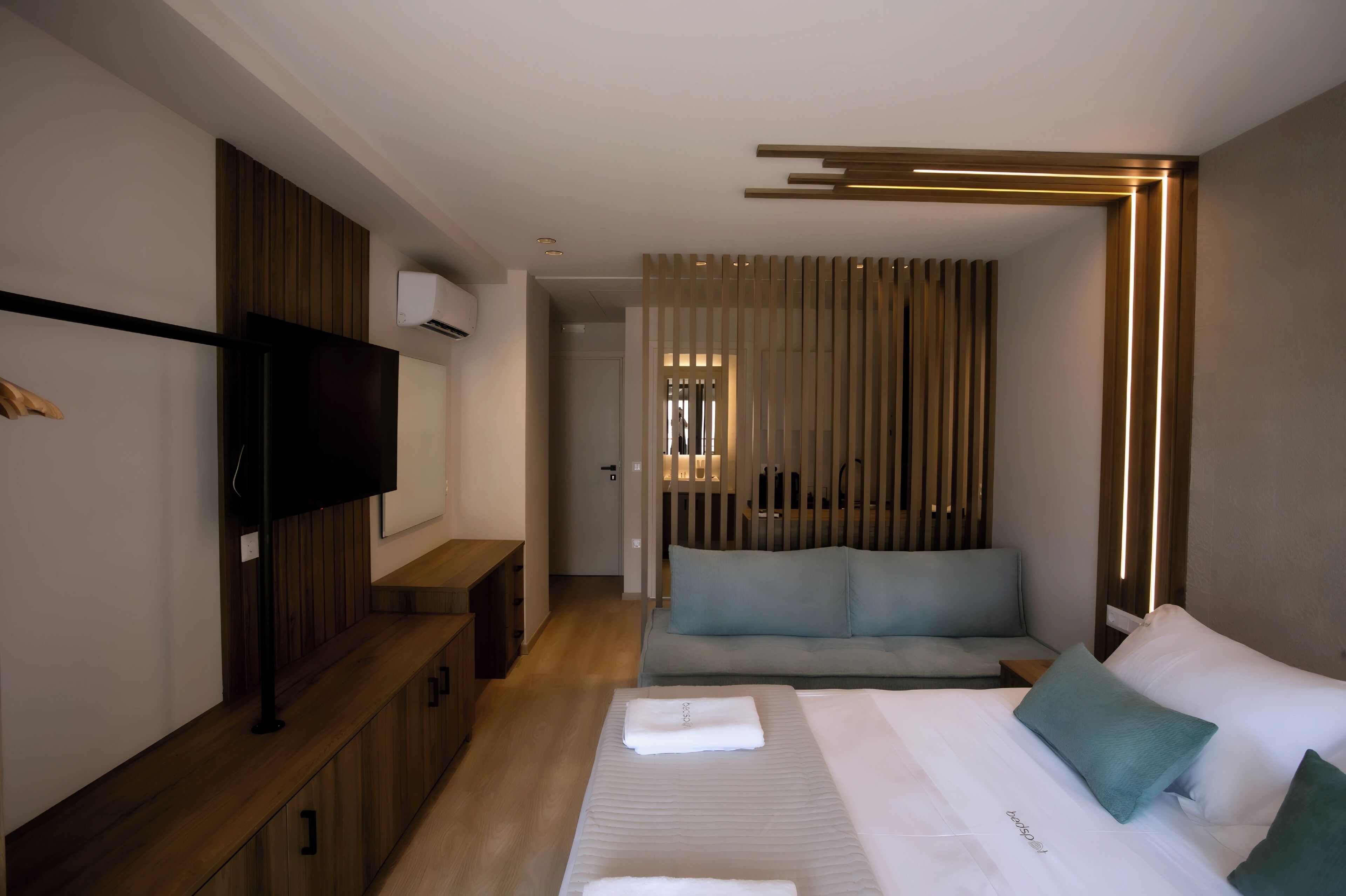 A modern hotel room with a bed, a seating area, and a TV.