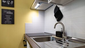 A kitchen with a stainless steel sink, a black pot rack, and a sign listing herbs like parsley and rosemary. - Romantic loft with private garden | Self check-in (Verona)