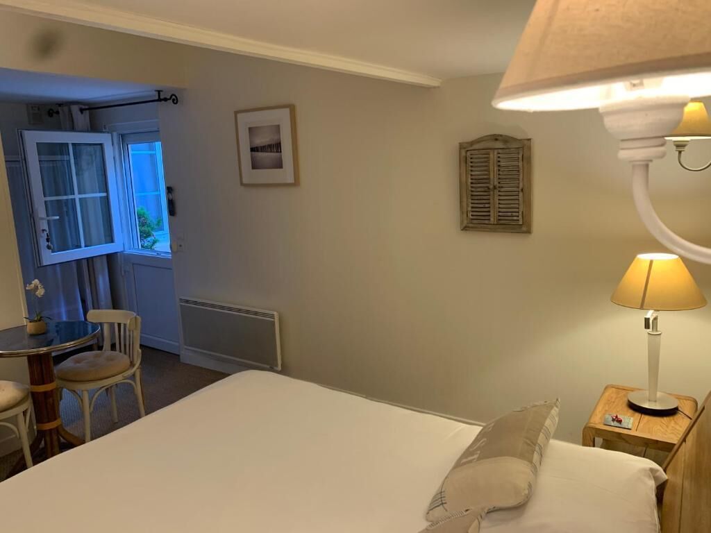 Une chambre à coucher avec un lit, une table de chevet, une lampe, une fenêtre et une vue sur l’extérieur.
