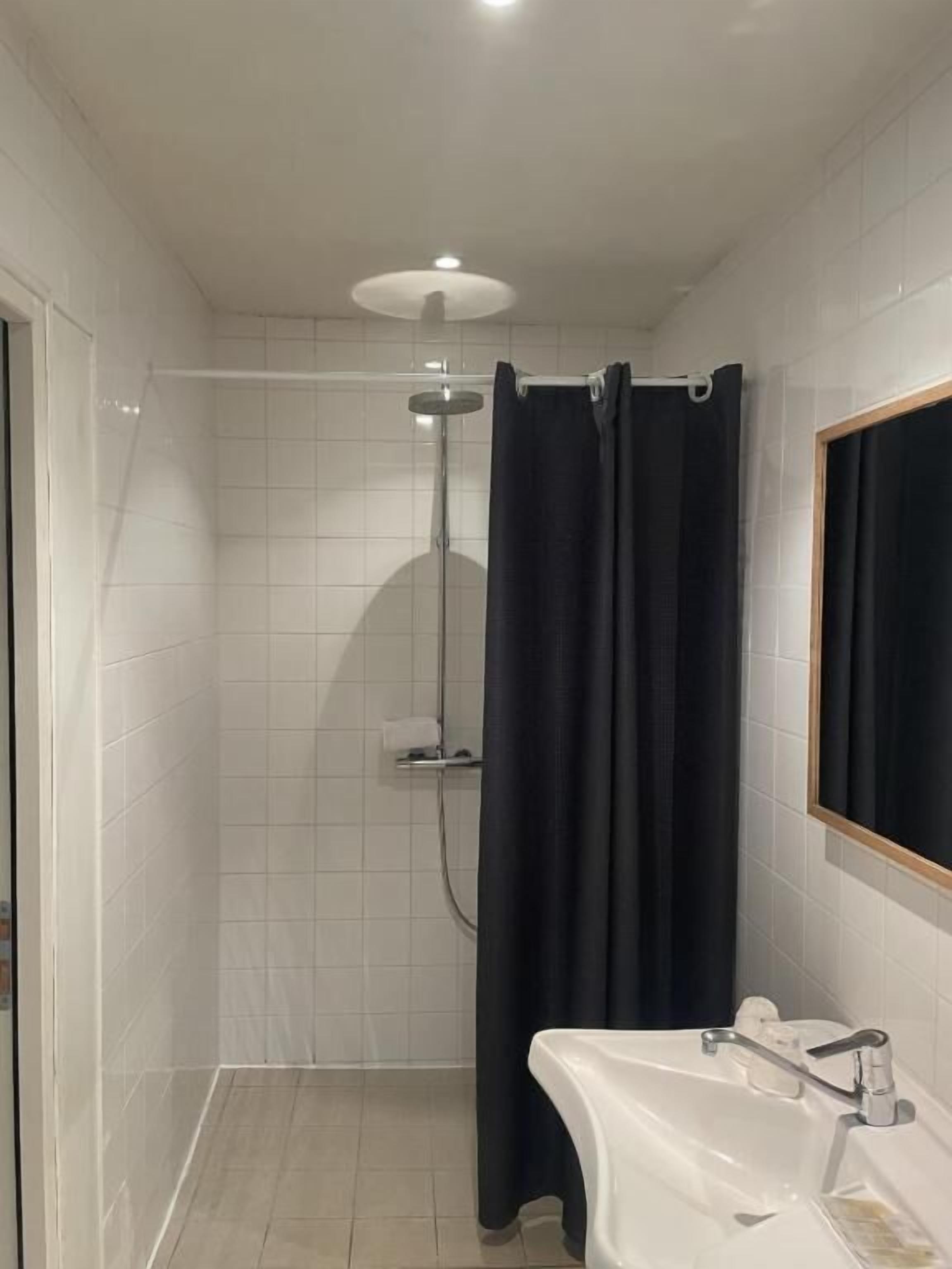 A bathroom with a shower, a sink, and a mirror.