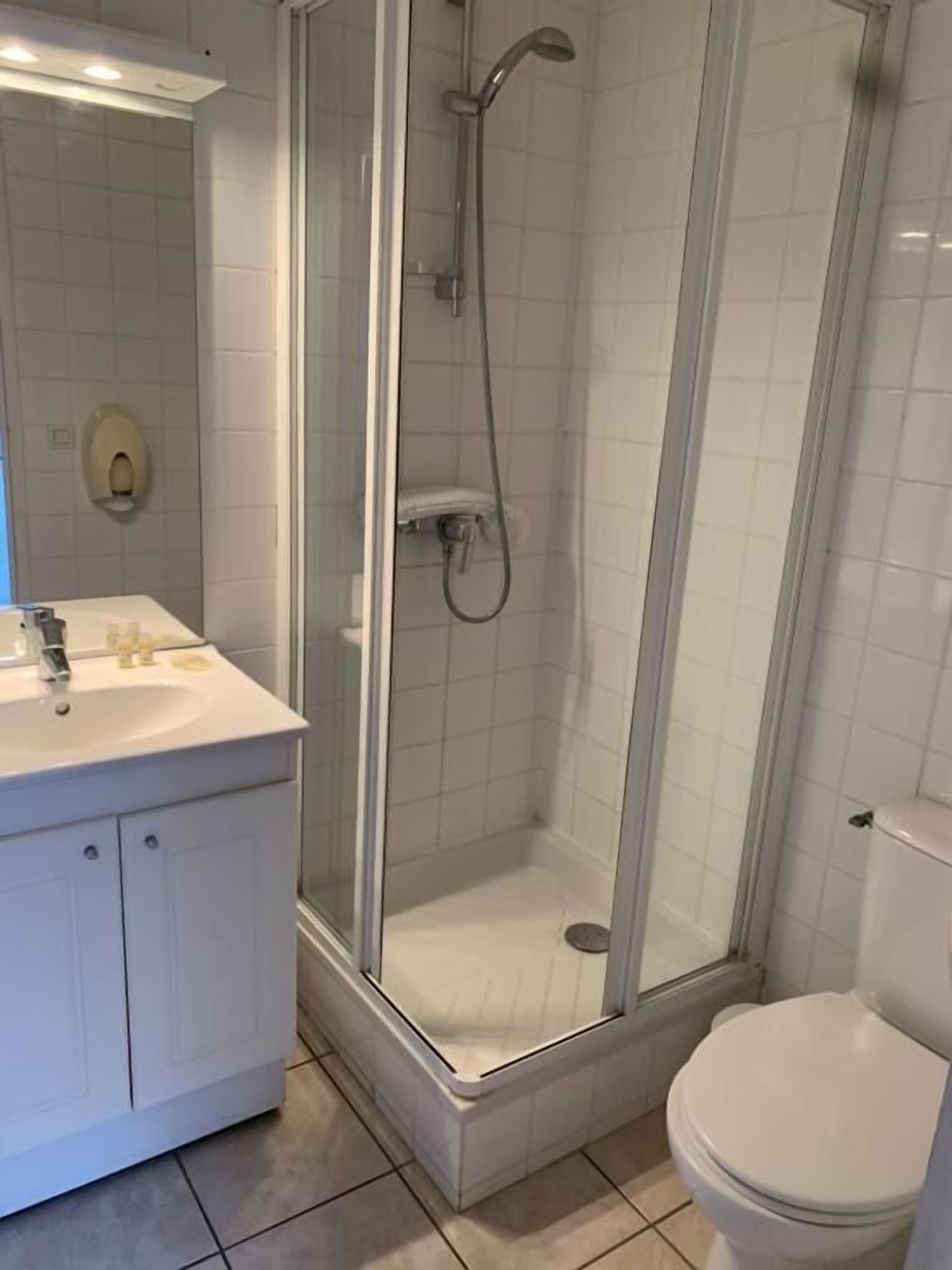 A bathroom with a glass-enclosed shower, a white sink, and a toilet.