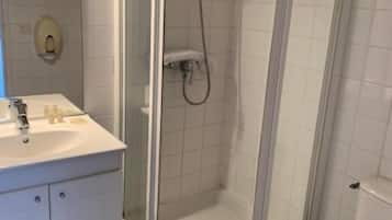 A bathroom with a glass-enclosed shower, a white sink, and a toilet.