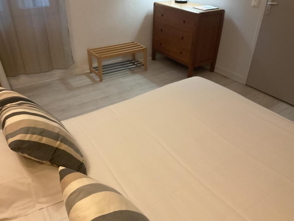 Een slaapkamer met een bed, een houten nachtkastje, een kleine tafel en een kledingkast.